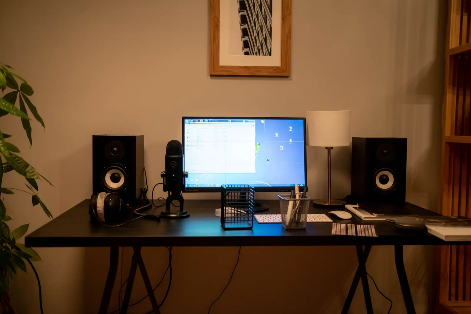 A computer monitor and speakers on a desk in a warmly lit room