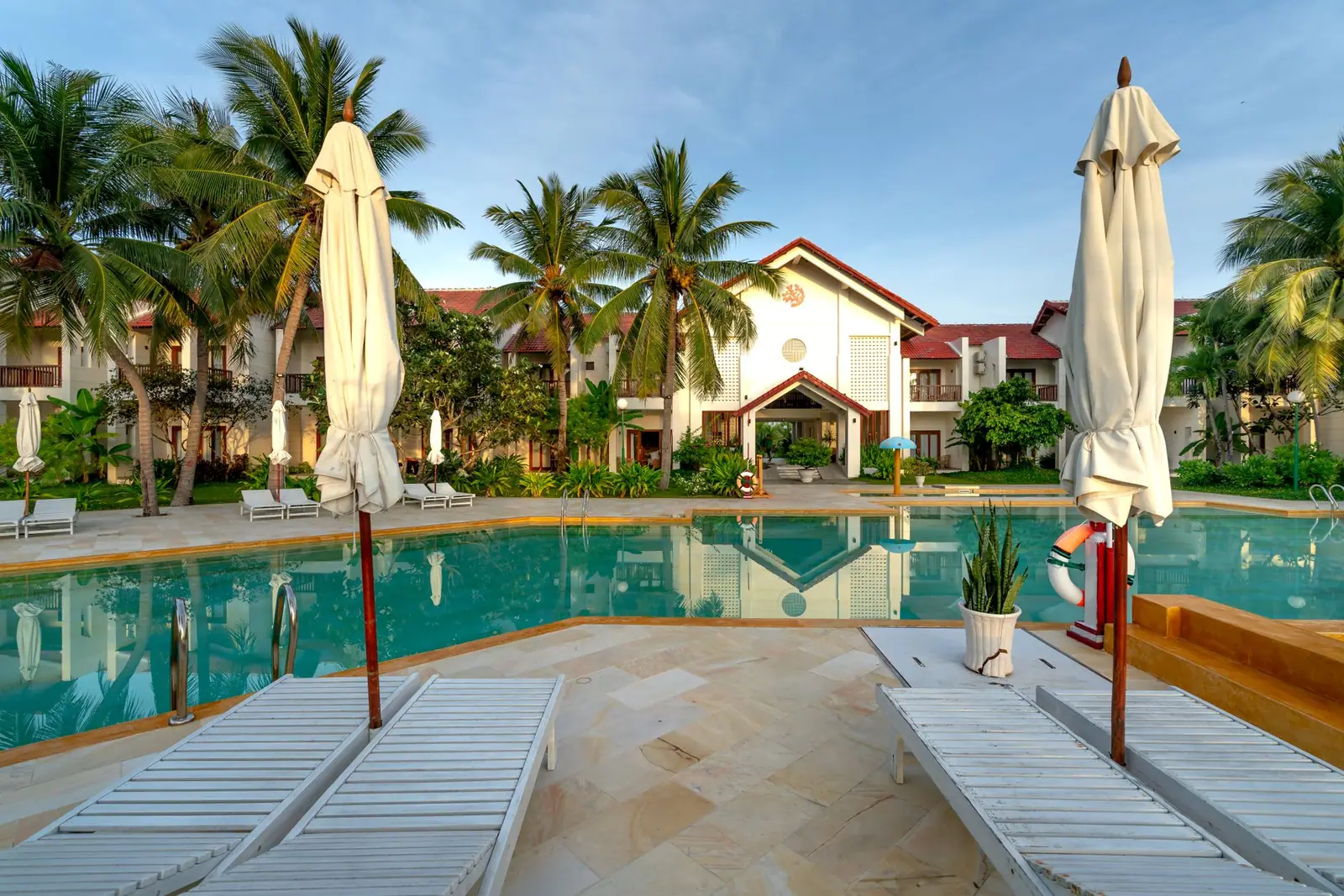 An empty pool with loungers and closed umbrellas around it