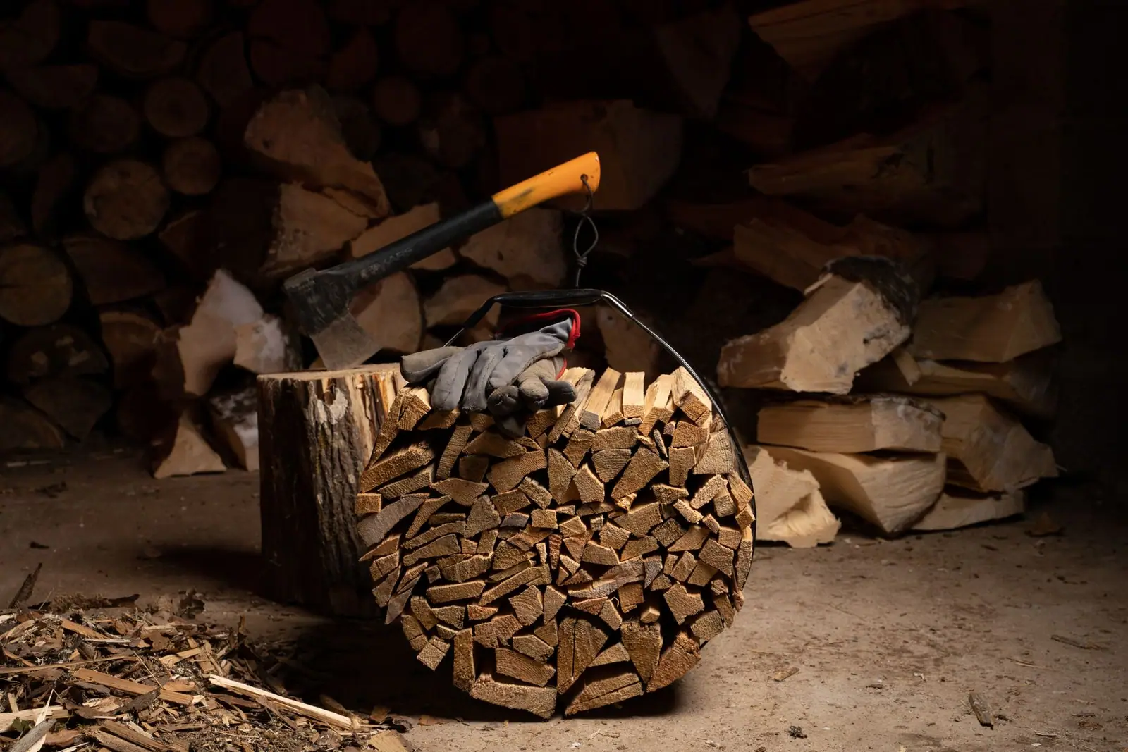 A splitting axe standing in a log in front of a woodpile