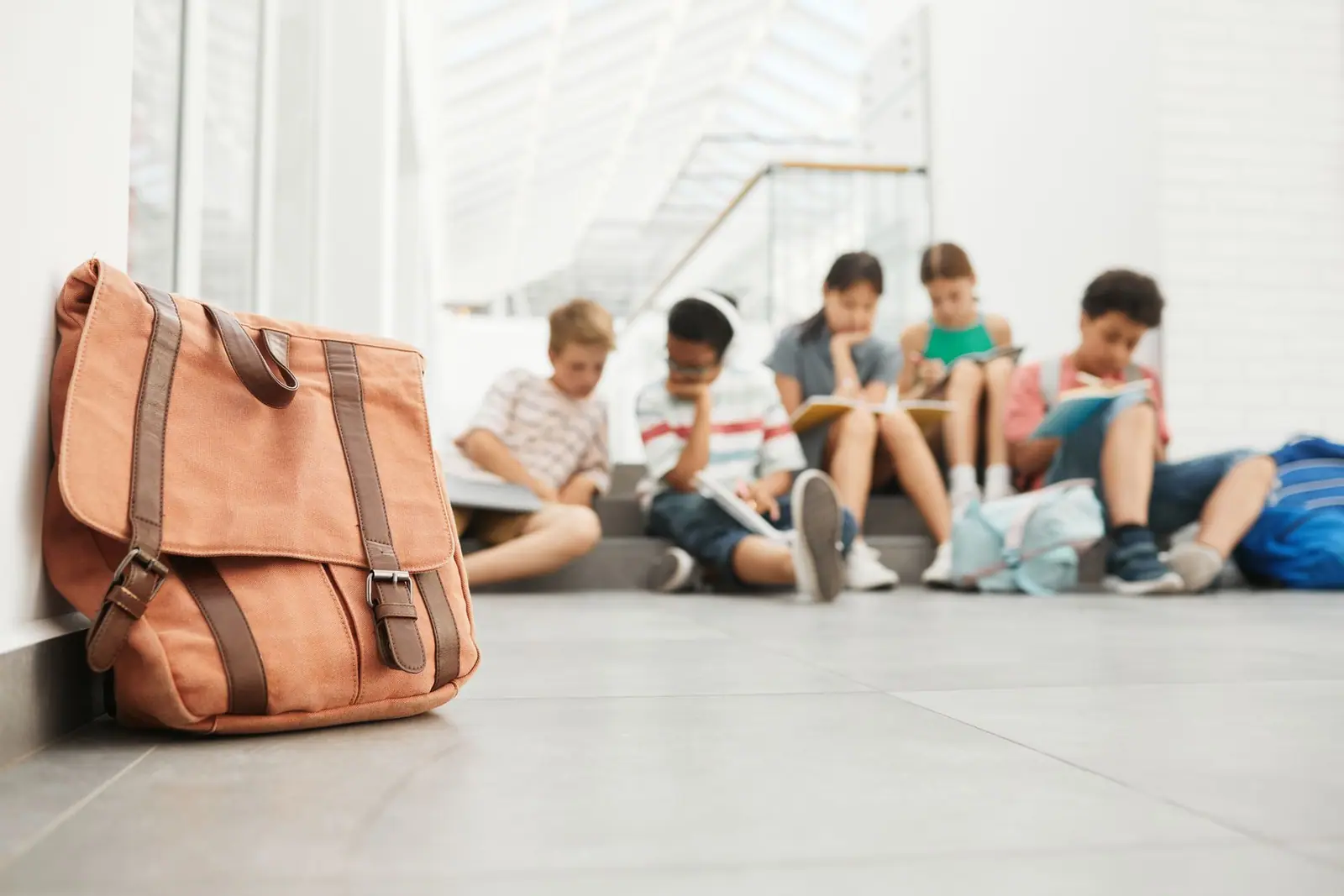 A packed shoulder bag standing on the floor against a wall