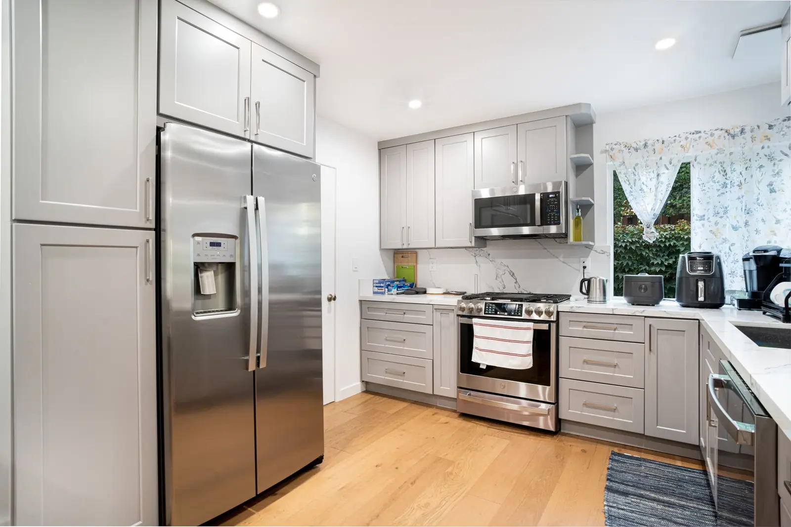 A stainless-steel side-by-side refrigerator beside white kitchen cabinets and a built-in oven