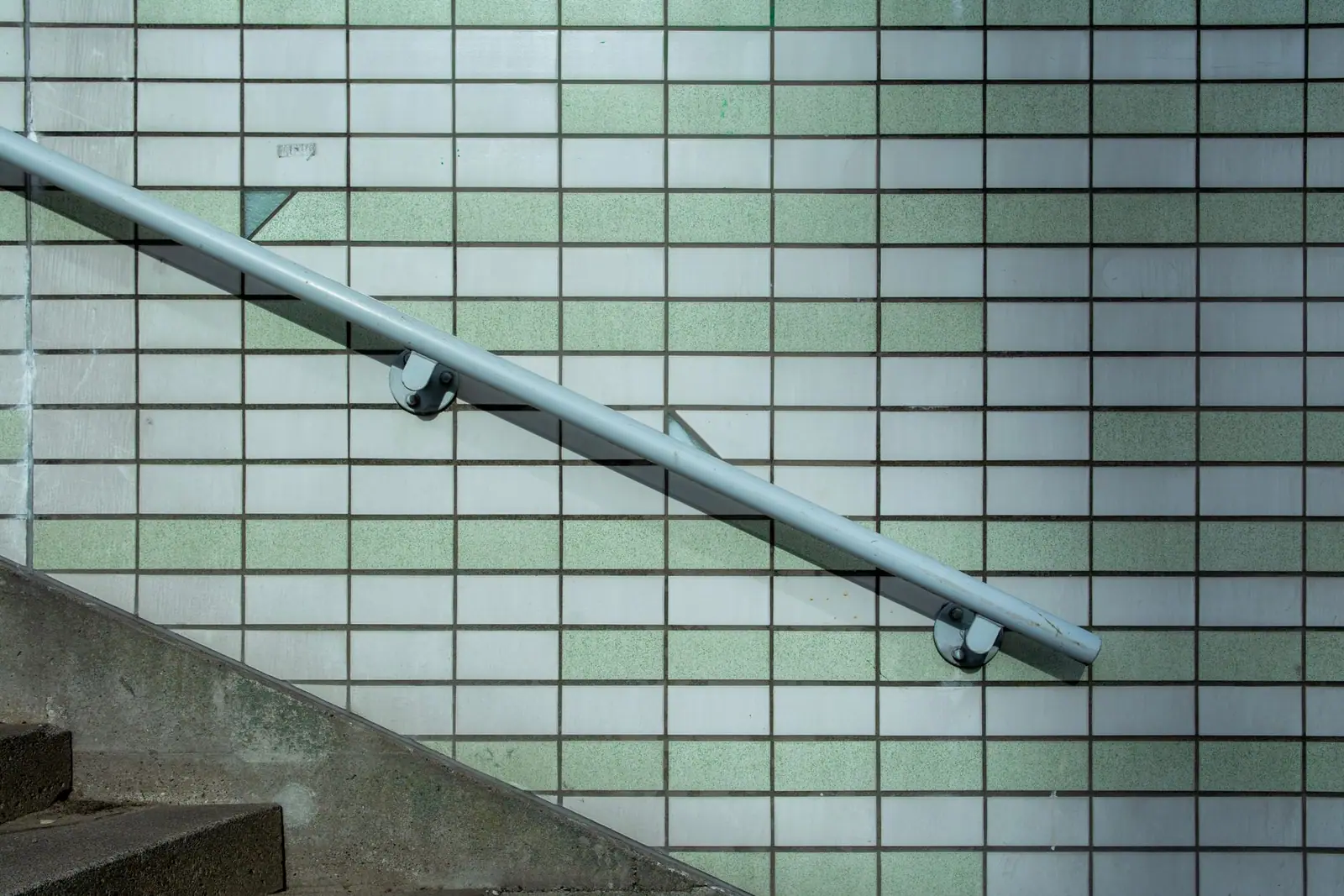 A metal handrail fixed to a tiled wall