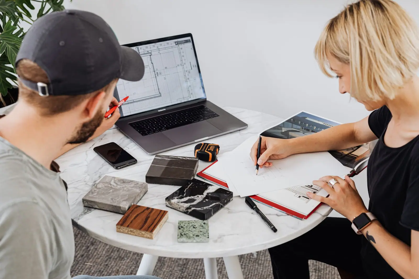 Two people reviewing drawings and material samples across a table