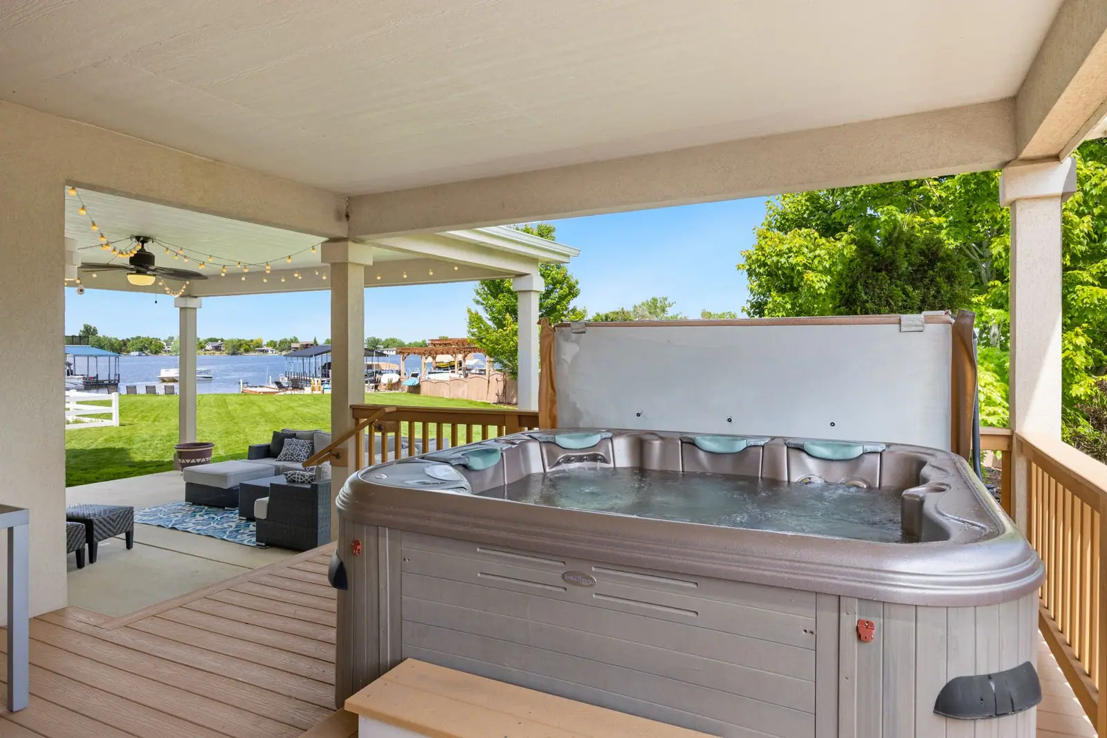 An acrylic hot tub on a covered deck with its cover lifted