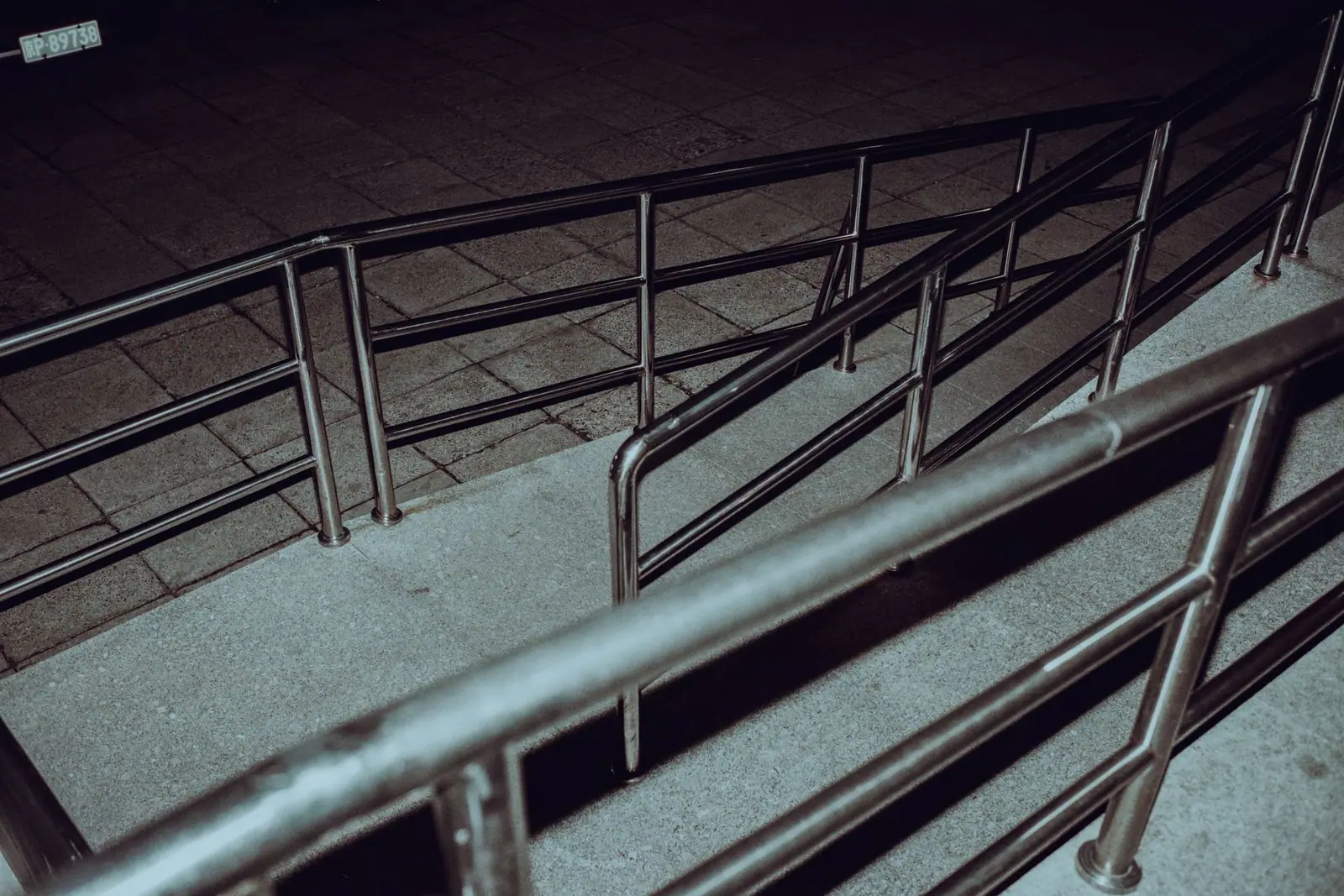 A ramp with metal handrails rising alongside a wall