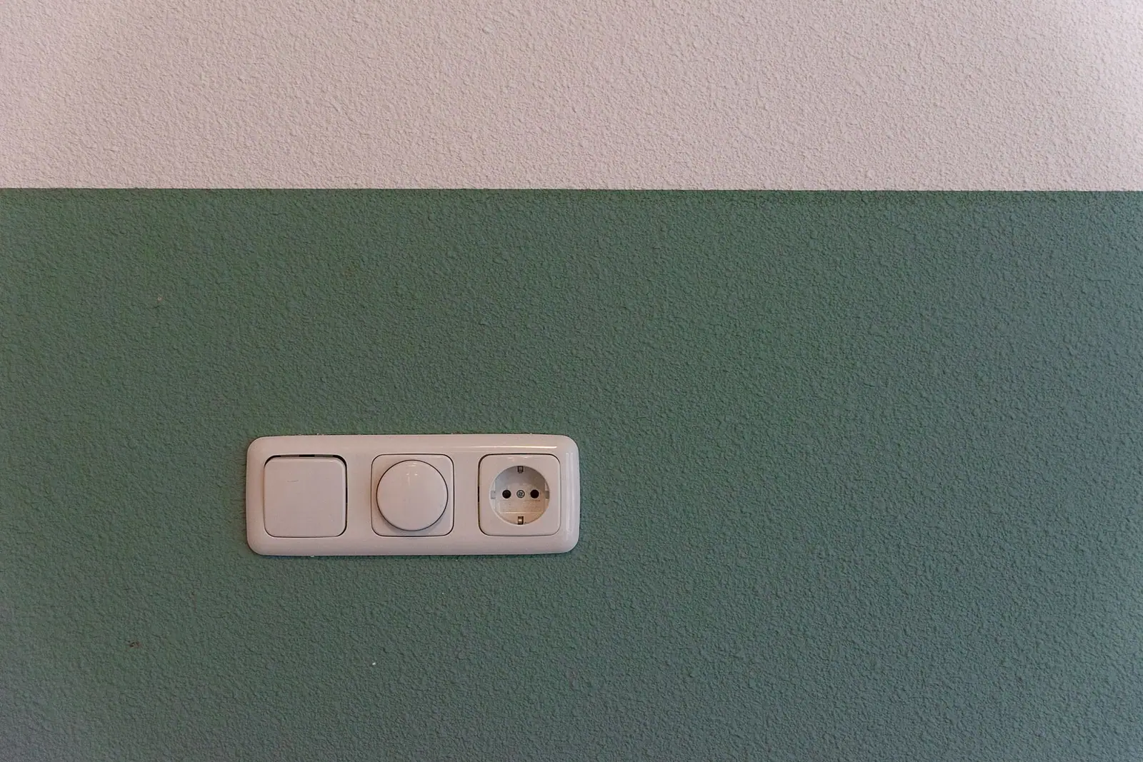 A light switch and a wall socket on a painted wall