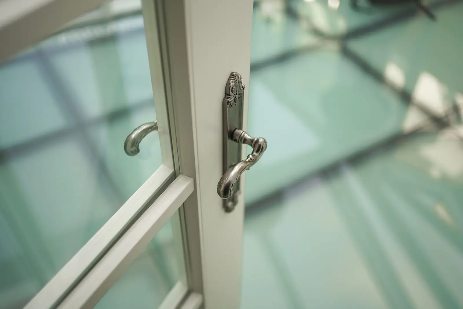 A curved metal handle and lock fitted to a white glazed patio door